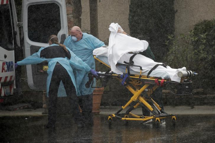 Medics transport a patient through heavy rain into an ambulance at Life Care Center of Kirkland